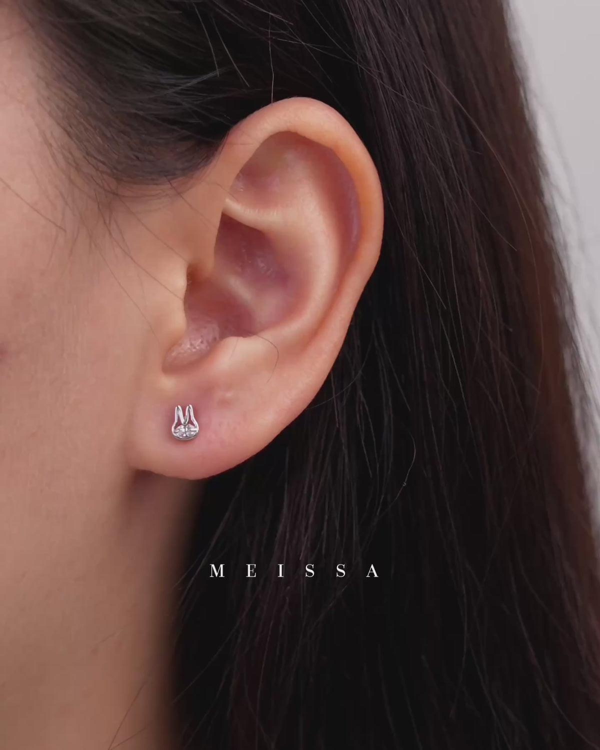 Video showing Meissa Bunny Sparkle Screw Back Earrings in 925 sterling silver with moissanite, featuring close-up ear shots, a finger pointing to the earring for scale, and the pair displayed on fingertips to highlight their small size and bunny design.